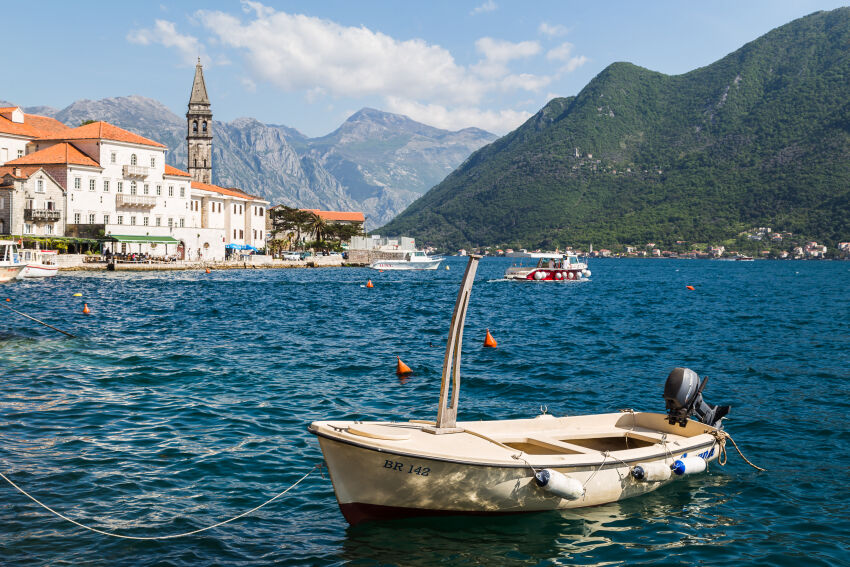 The old houses of Perast behind the motorboat rocking on the waves